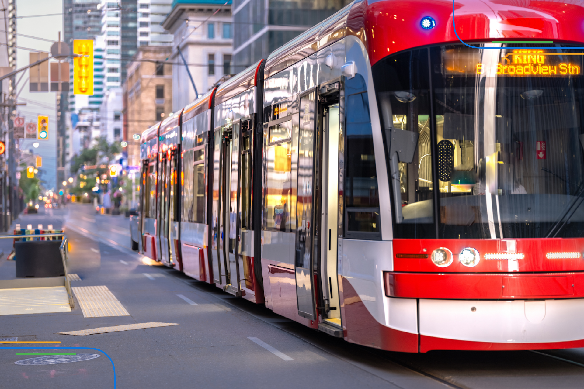 a red Toronto streetcar coming to a stop at the side of the road