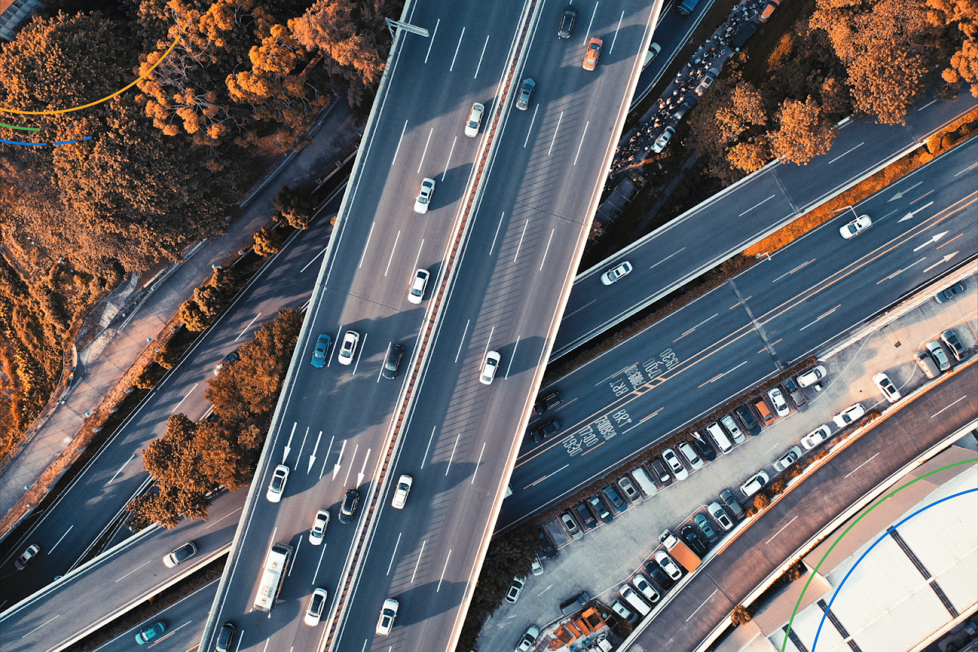 a bird’s eye view of cars moving on a highway surrounded by trees