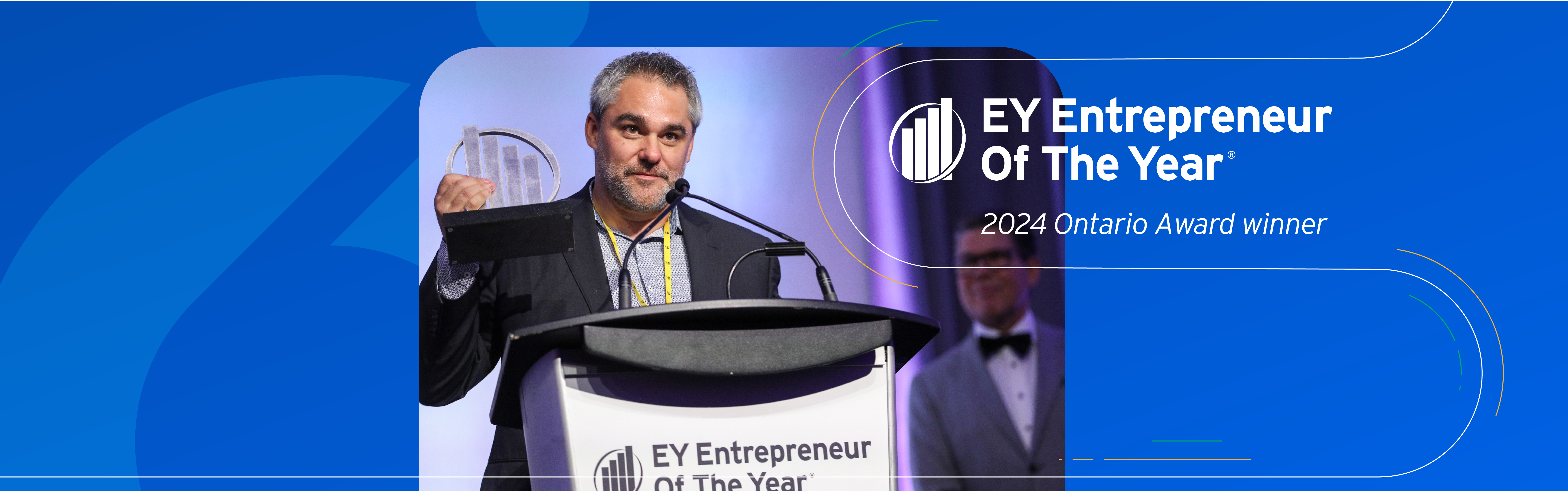 Miovision co-founder and CEO, Kurtis McBride, stands at a podium holding an EY Entrepreneur of the YearⓇ Ontario award