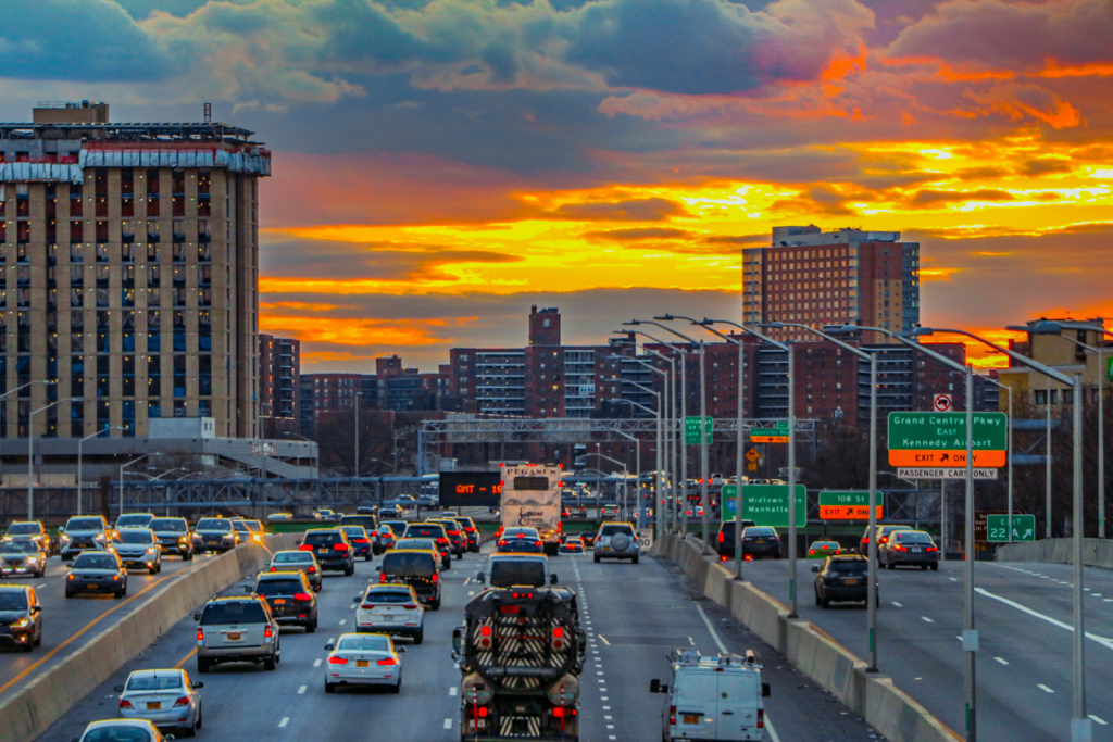 A busy, urban highway with traffic heading toward the city in the distance.