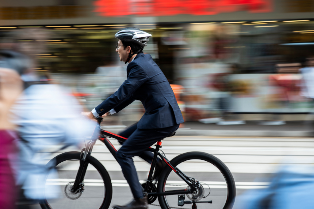 A man in business attire cycles on a city street.