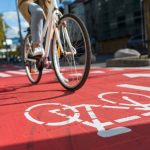 A cyclist rides along a road featuring a red section marked with a white bike symbol.