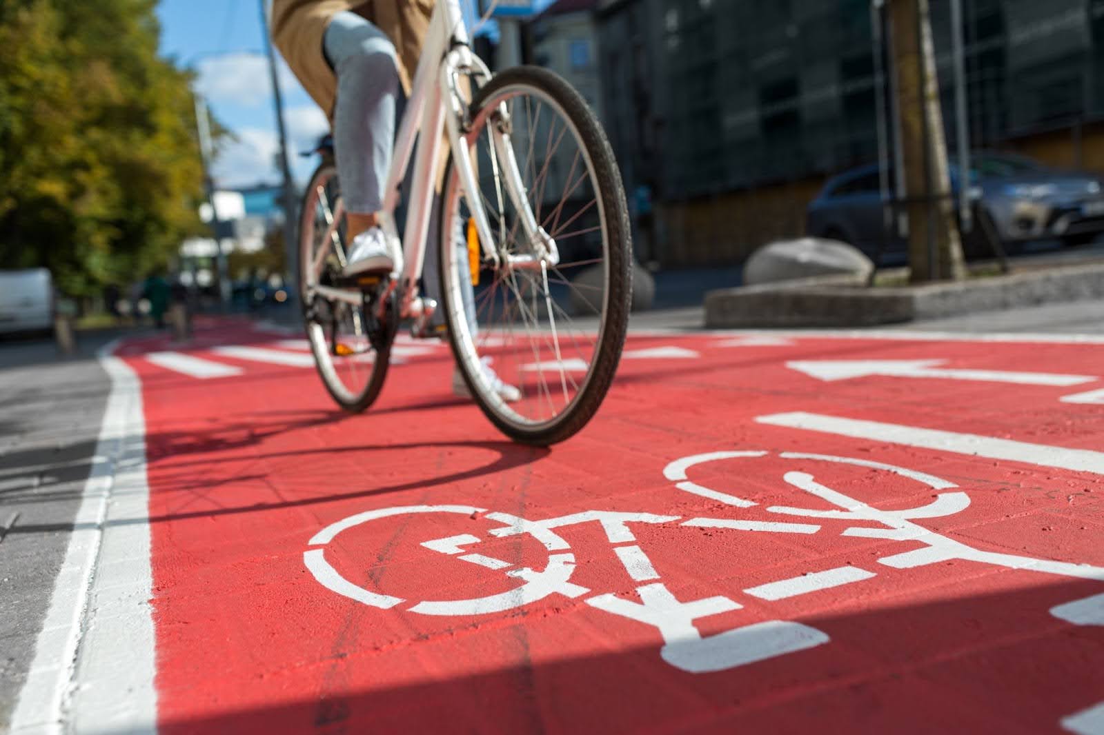 A cyclist rides along a road featuring a red section marked with a white bike symbol.