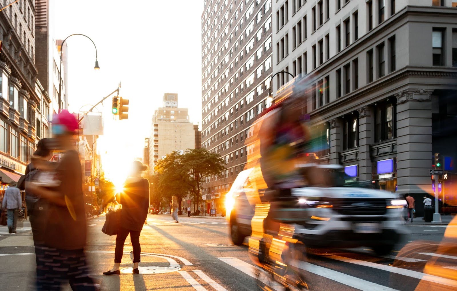 A busy intersection with blurred bicyclists, pedestrians, and cars showing rapid movement.