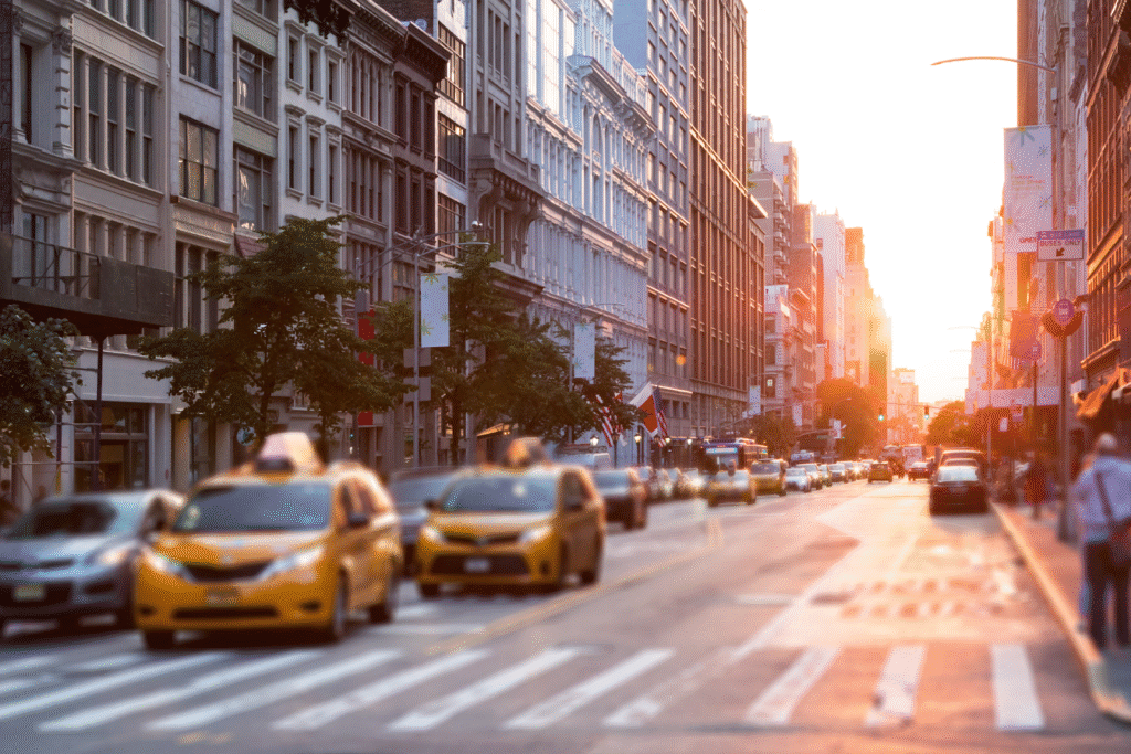 A sunset at a New York City intersection, taxis and other vehicles on the road.