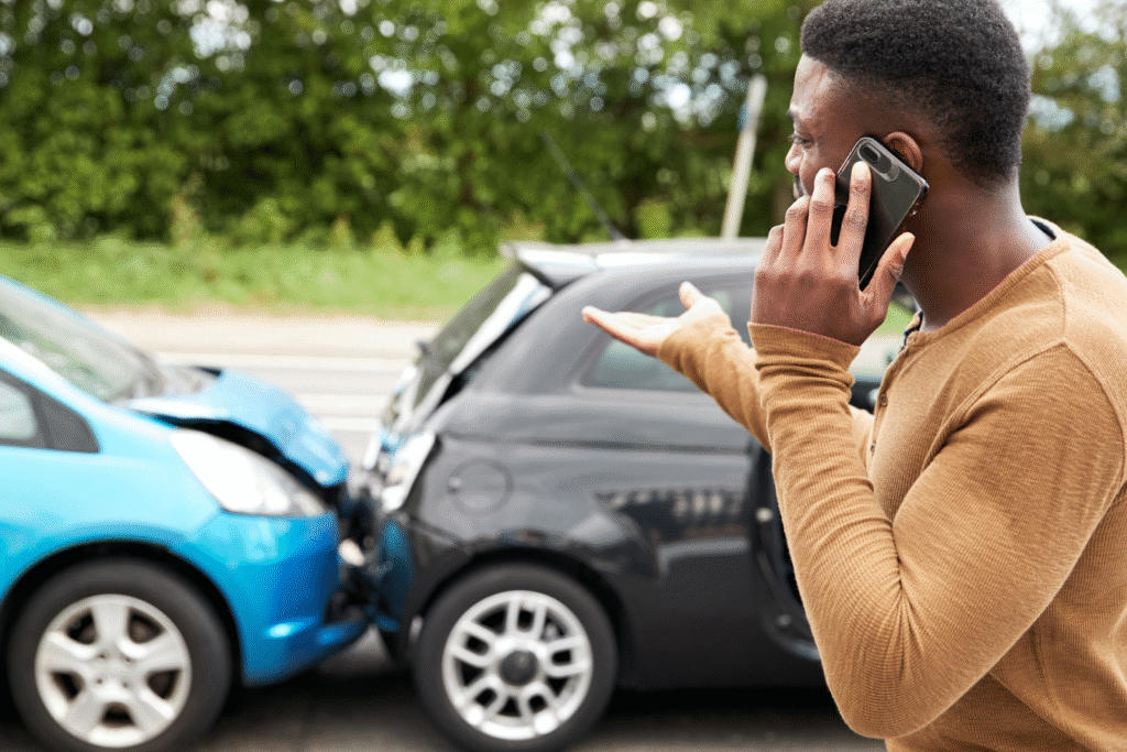 A man on the phone looks at a car accident.