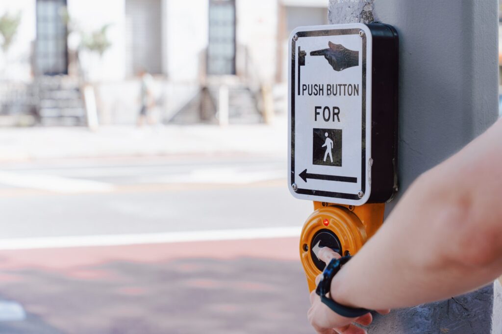 Person pressing pedestrian crossing button at crosswalk