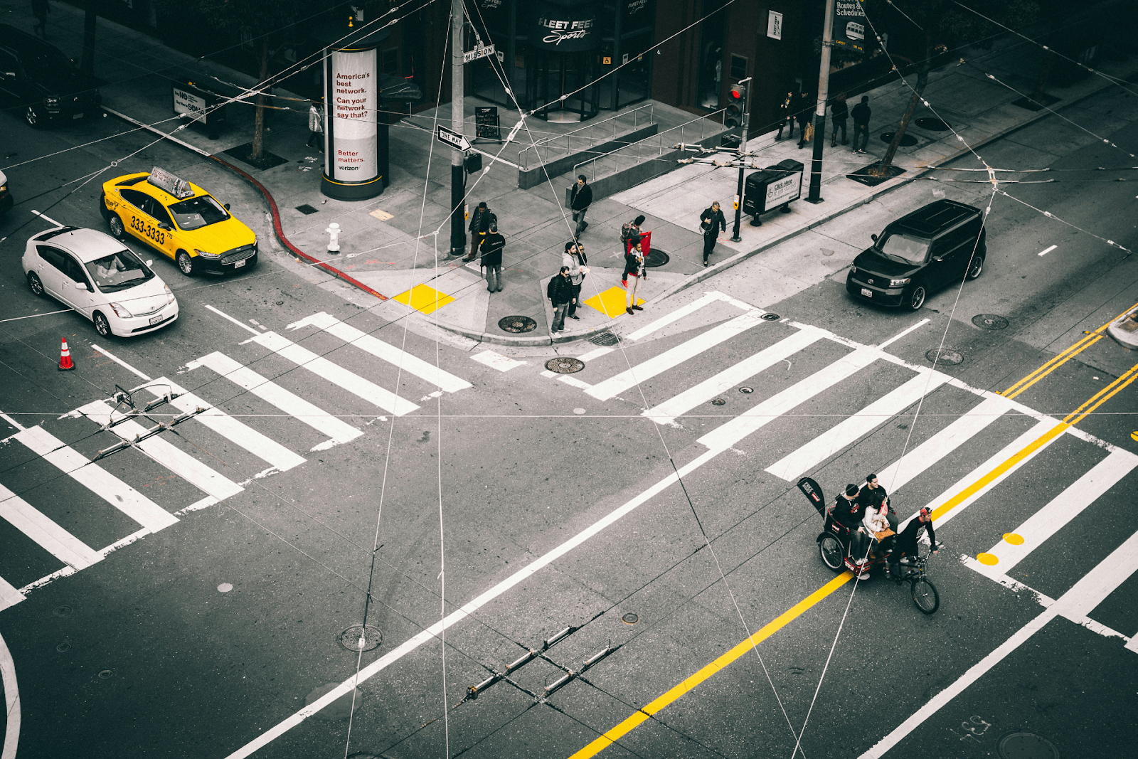 The corner of an intersection with cyclists, pedestrians, and cars