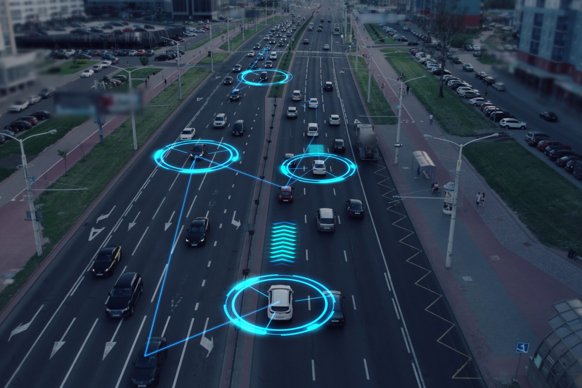 A multi-lane city roadway with moderate traffic, viewed from above, where several cars are highlighted with glowing blue digital overlays and connecting lines