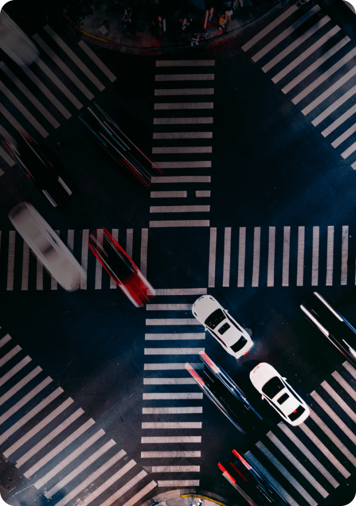 Aerial view of a busy city intersection at night, with vehicles moving through crosswalks
